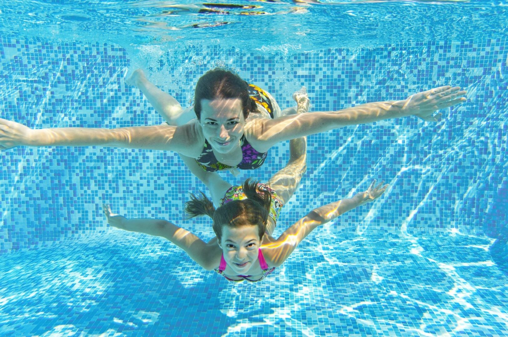 Two children swimming in a pool with their arms outstretched.