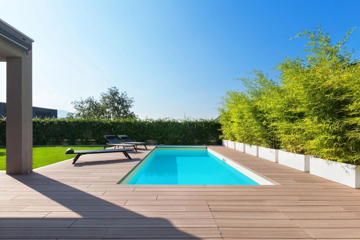 A swimming pool with a bench and trees in the background.